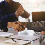 Business people shake hands while signing a business agreement