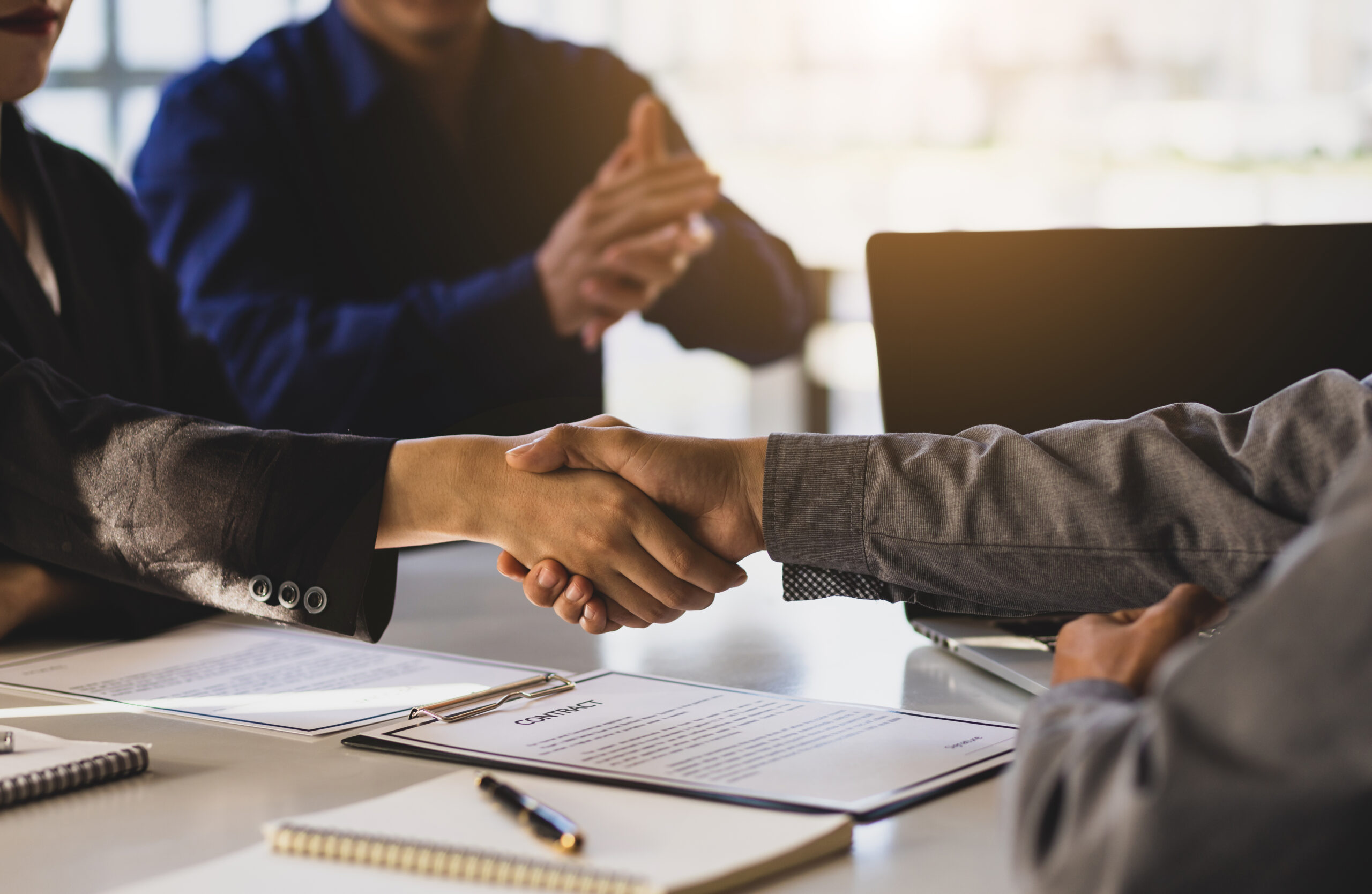 Business people shake hands while signing a business agreement